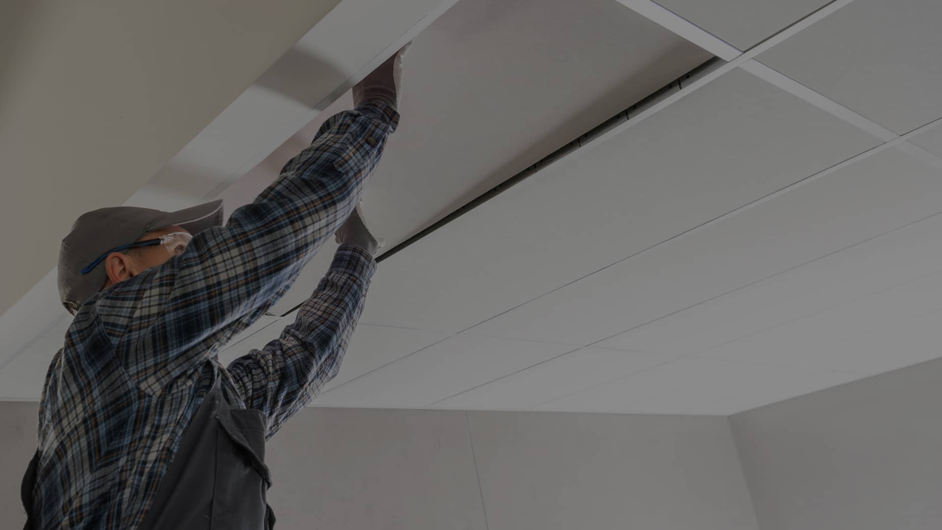 Travailleur de chantier installant le plafond suspendu à l’intérieur d’un bâtiment commercial
