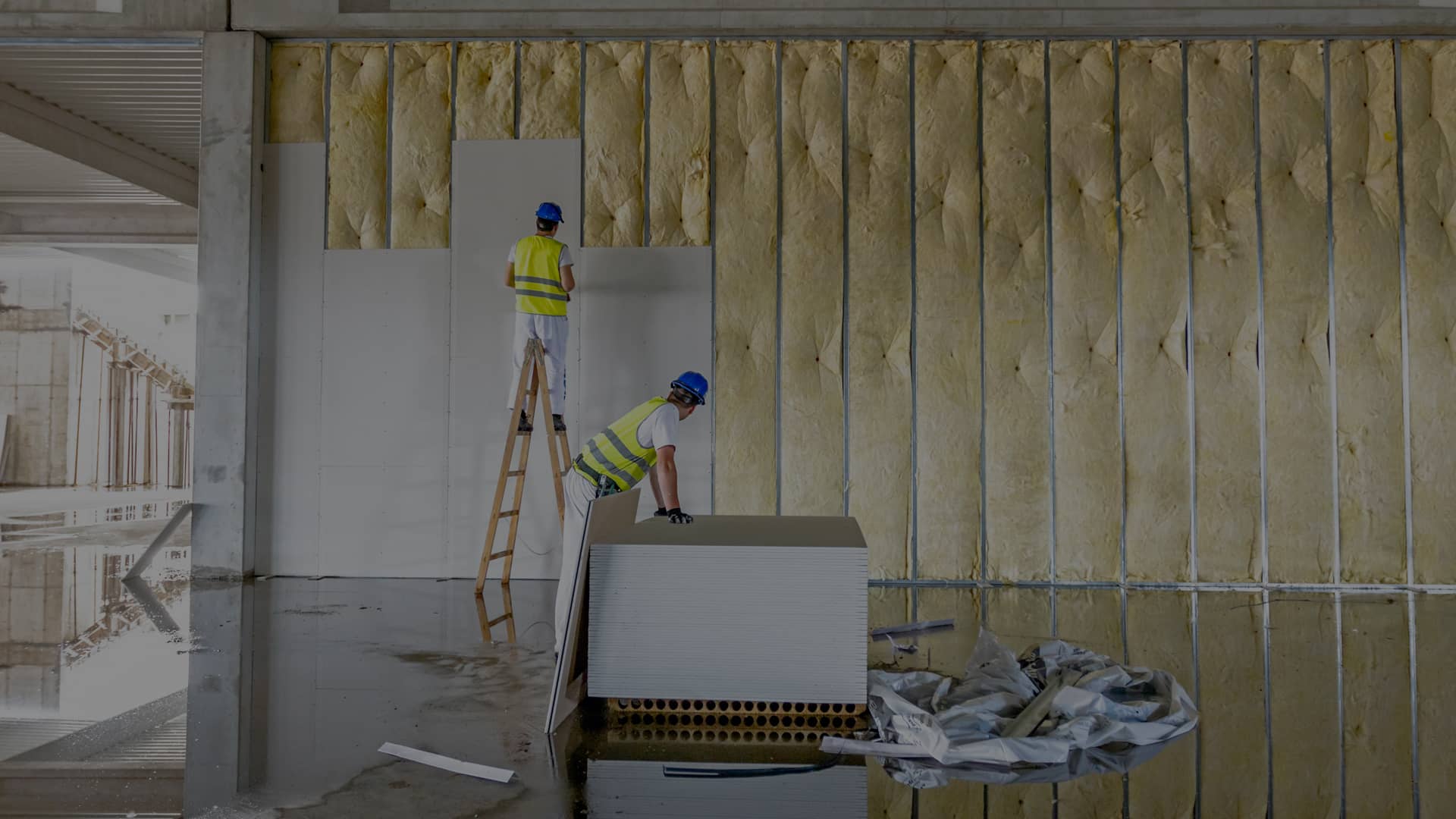 Les travailleurs assemblent le mur de gypse. Les plaques de plâtre sont en construction à l’aide d’une échelle en bois.